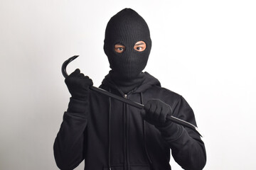 Thief wearing black jacket and mask holding crowbar, isolated on white background.