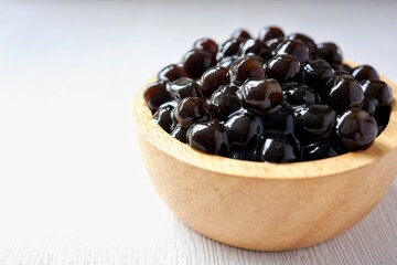 Black pearls for bubble mllk tea in a wooden bowl on white background