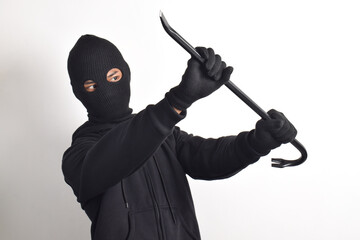 Thief wearing black jacket and mask holding crowbar with fear pose, isolated on white background.