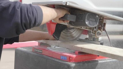 A table saw is actively cutting through a wooden board, showcasing the precision and power of the tool in a workshop setting.