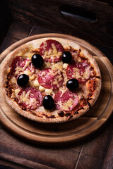 Pizza with salami, mozzarella and cheddar cheese. Wooden background. Soft focus. Close up.