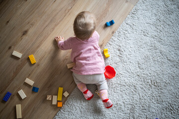 Naklejka premium A small child plays with a construction set. Top view.