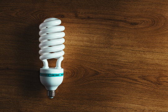 Bombilla LED grande y ecológica que representa eficiencia energética y sostenible. Concepto de conciencia ambiental y ahorro de energía. El fondo de madera acentúa la responsabilidad ambiental. - Powered by Adobe