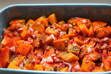 Sheet pan with pieces of butternut squash, onion, herbs and spices. Preparing pumpkin for a roast....