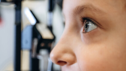 Close up view. Little girl is checking vision in the ophthalmologist cabinet