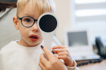Covering the eye. Little boy is having check up in the ophthalmologist cabinet