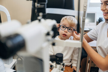 In the new glasses. Little boy is having check up in the ophthalmologist cabinet