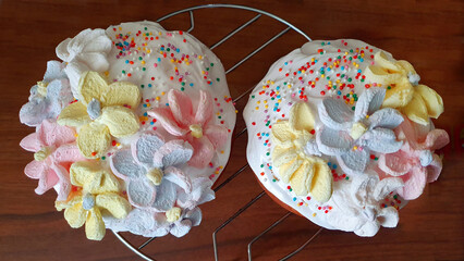 Two Easter cakes decorated with marshmallow flowers. On a chrome stand, top view.	