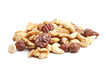 A pile of assorted nuts including walnuts, pecans, hazelnuts, cashews, and almonds displayed on a white surface, showcasing texture and natural appeal