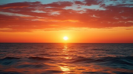 Obraz premium A stunning sunset over the ocean, casting vibrant orange and yellow hues across the sky and reflecting shimmering light on the water's surface.