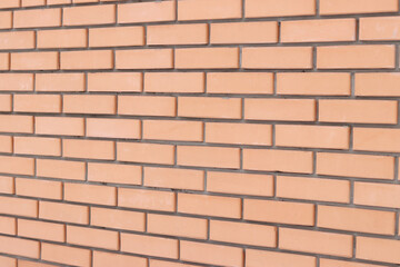 Obraz premium Brick wall side view background. Orange brick wall background for exterior design. Construction concept, outdoor buildings, garage or house. Wall with classic checkerboard pattern and visible joints