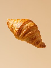 A golden croissant on a soft beige background
