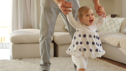Fototapeta premium Close Up Of Father Helping Baby Daughter To Take First Steps At Home