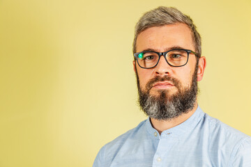 Fototapeta premium Man with glasses and beard poses against a yellow background