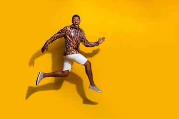 Man in vibrant tiger-patterned shirt jumping energetically against bright yellow backdrop