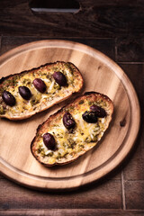 Bruschetta with mozzarella and cheddar cheese, olive pesto and kalamata olives. on wooden background. Soft focus. Close up	