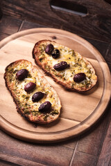 Bruschetta with mozzarella and cheddar cheese, olive pesto and kalamata olives. on wooden background. Soft focus. Close up	