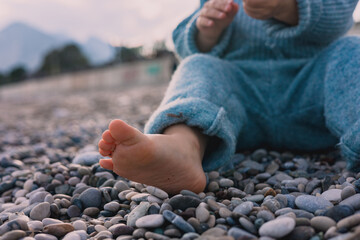 Child sitting on pebbled beach during a calm day by the sea