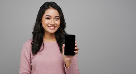 Fototapeta premium Smiling Young Asian Woman Holding Smartphone with Blank Screen Studio Shot