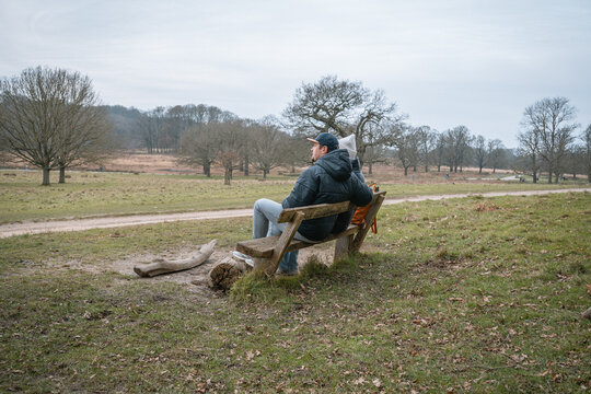 Richmond Park. A couple sits closely on a rustic wooden bench