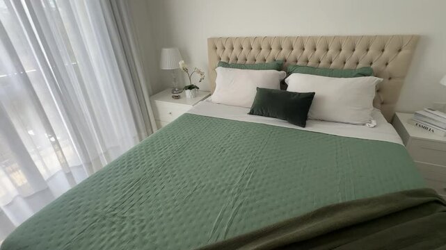 quarto com cabeceira em captone confortavel com cama arrumada em tons verdes e brancos 