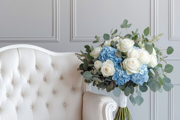 Elegant bridal bouquet with deep blue hydrangeas, soft white roses, and silver-green eucalyptus, displayed on a classic white chair.