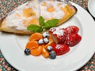 Thin pancakes with cottage cheese, garnished with fresh fruit. Perfect for themes of traditional Polish cuisine, homemade food, and designs highlighting fresh ingredients and culinary traditions.