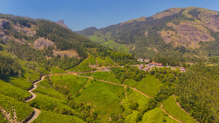 Obraz premium Drone Shot of Munnar’s Charming Village and Rolling Tea Estates