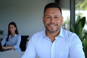 An office with an open space layout is where a businessman wearing a shirt is working on his laptop