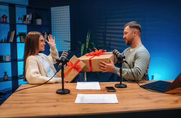 Two people are in podcast room holding new year Christmas gift boxes