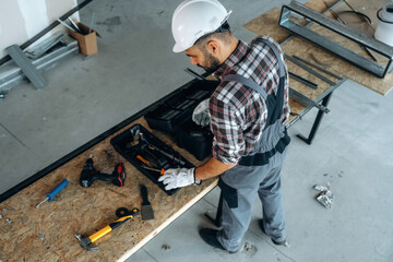 Wooden table with metal foundation. A man is renovating an unfinished room