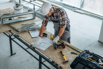 Top view, standing by the table. A man is renovating an unfinished room