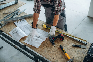 Focused, tools. Close up view of worker that is renovating unfinished room