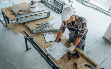 By the table. A man is renovating an unfinished room