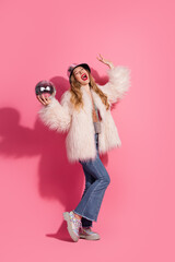 Stylish young woman posing with disco ball against pink vertical background, celebrating glamour...