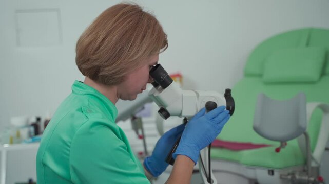 Gynecologist using colposcope, magnifying optical device designed for thorough examination of cervix, vagina, and vulva, helping to diagnose abnormalities and detect precancerous conditions. 