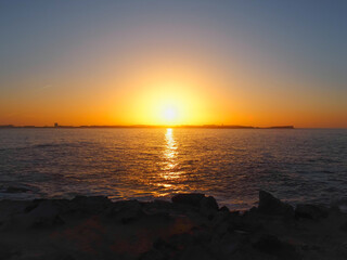 Golden yellow sunset in the coast of Atlantic ocean. Terrain of Peniche peninsula visible in the distance from Baleal, small island located in the north of Peniche. Oeste region of Portugal.
