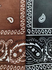 Two pieces of fabric showcase elaborate paisley designs, one in a warm brown hue and the other in a...