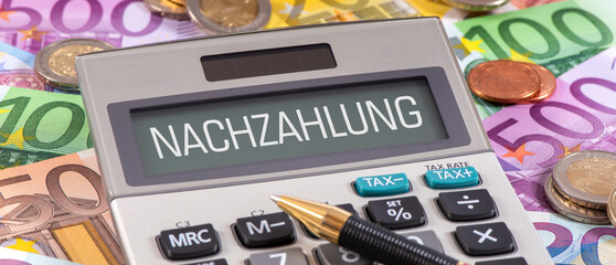 Ein Taschenrechner liegt auf vielen Euro Geldscheinen mit der Display-Aufschrift Nachzahlung -...