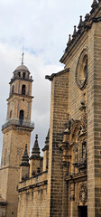 Jerez de la Frontera; historic church with a tall bell tower, ornate stone fa&ccedil;ade, and decorative sculptures; cloudy sky in the background;