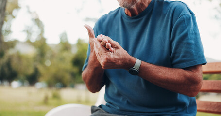 Senior, man and hands with injury, pain or ache for fibromyalgia or muscle tension on park bench....