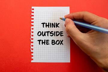 Think outside the box message written on white paper on red background. Conceptual think outside the box symbol. Copy space.