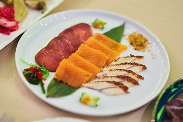 A plate with various types of fish. The plate is placed on the table along with other plates of food