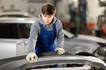 Guy worker removes dents on cars exterior, restores vehicle to its original form. Male auto...