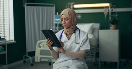 Obraz premium Arab doctor in hospital uses a tablet to coordinate treatment plans and review medical histories.