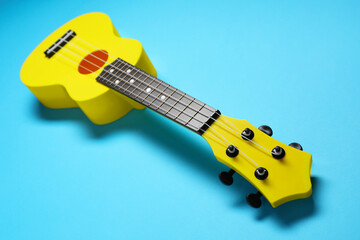 One ukulele on light blue background, closeup. String musical instrument
