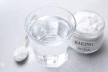 Glass of water and baking soda on white table, selective focus