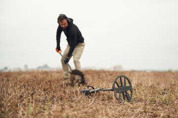 Digging the hole. Man is with metal detector in the field