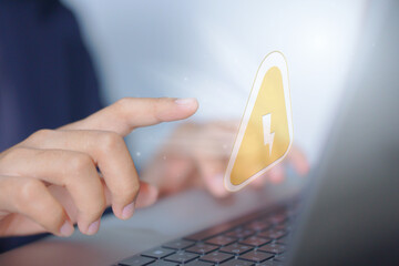 Cybersecurity and electricity risk concept, finger tapping digital energy alert on laptop