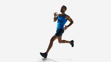 Low angle view of young male athlete, captured mid-run, showing strength, agility, and speed over...